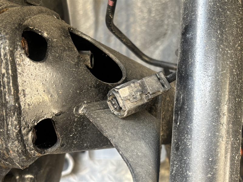 アクアNHP10のリア。バックプレートの裏側、トーションビーム付近にある車体側のABSセンサー配線のコネクタ