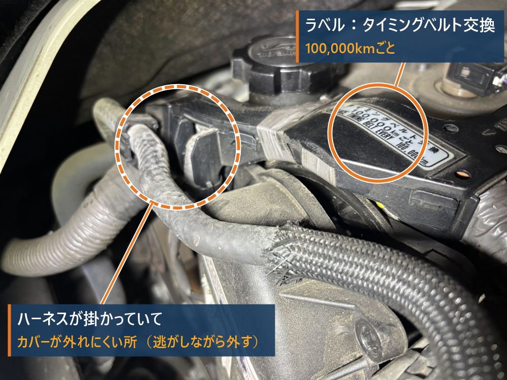 ハイエース1KD-FTVのタイミングベルトカバー上部。ハーネスが掛かっている部分と、タイミングベルト交換100,000kmのラベルを丸で囲んでいる